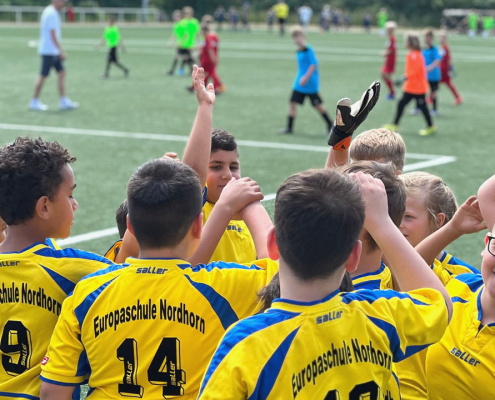 Gruppe von Kindern in Trikots der Grundschule Nordhorn klatscht sich ab bei Fussballturnier