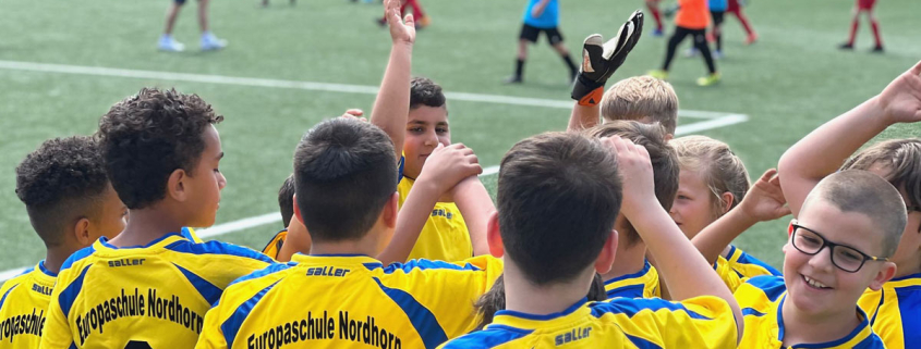 Gruppe von Kindern in Trikots der Grundschule Nordhorn klatscht sich ab bei Fussballturnier