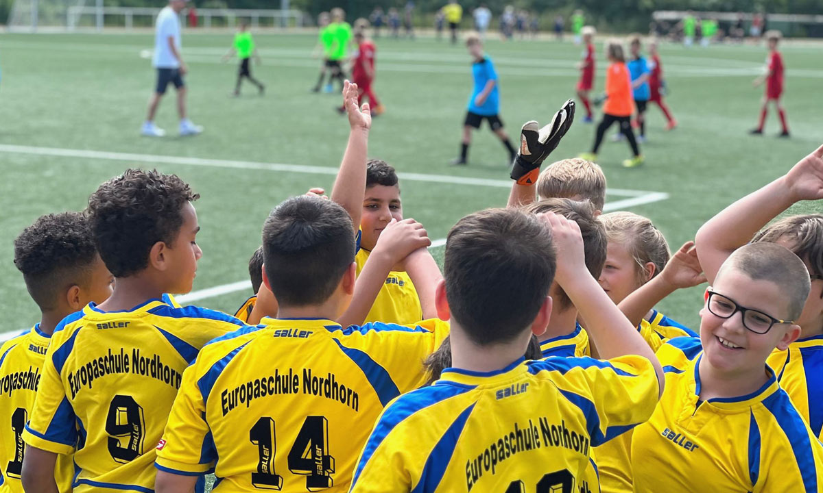 Gruppe von Kindern in Trikots der Grundschule Nordhorn klatscht sich ab bei Fussballturnier