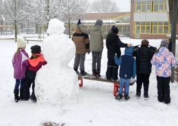 Kinder auf dem Schulhof mit Schneemann